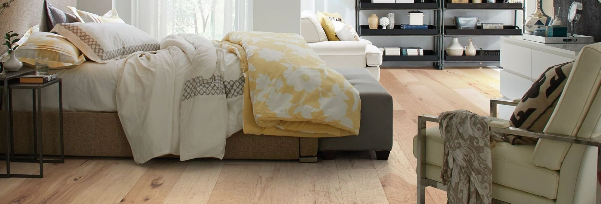 bed and armchair in bedroom with brown hardwood floor from Traditional Floors in Milan, IL